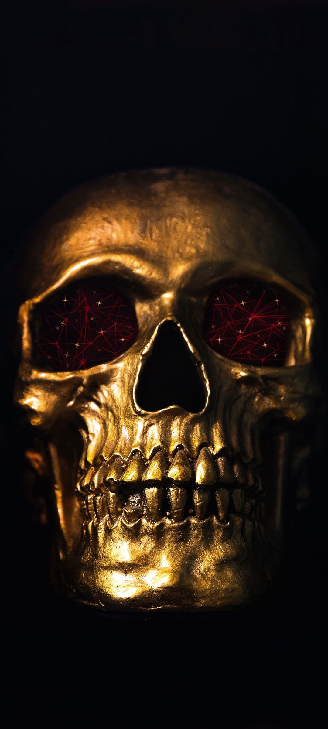 Golden metallic skull featuring glowing red geometric network lines within its eyes against a black background.