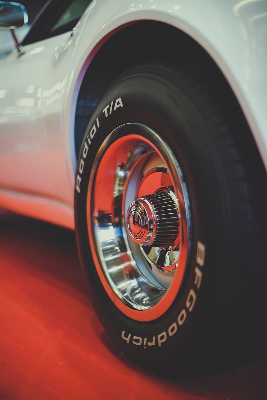 Classic BFGoodrich Radial T/A tire and polished chrome rim with orange accents on a bright red background.