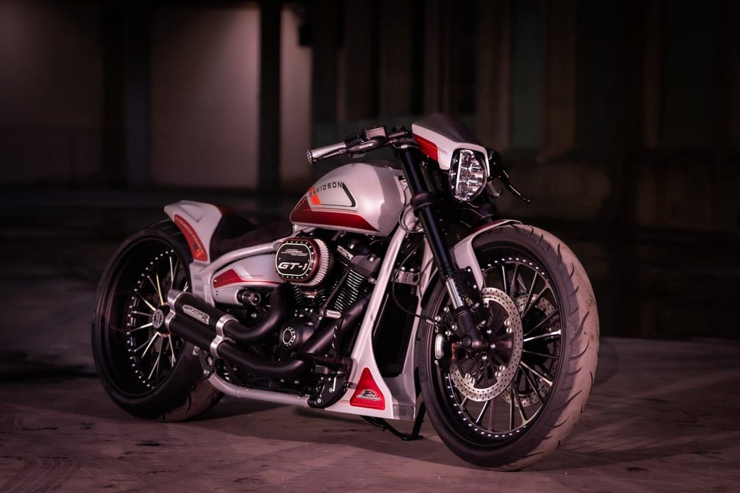 A custom silver and red Harley-Davidson FXDR motorcycle with a wide rear tire in a dark industrial space.