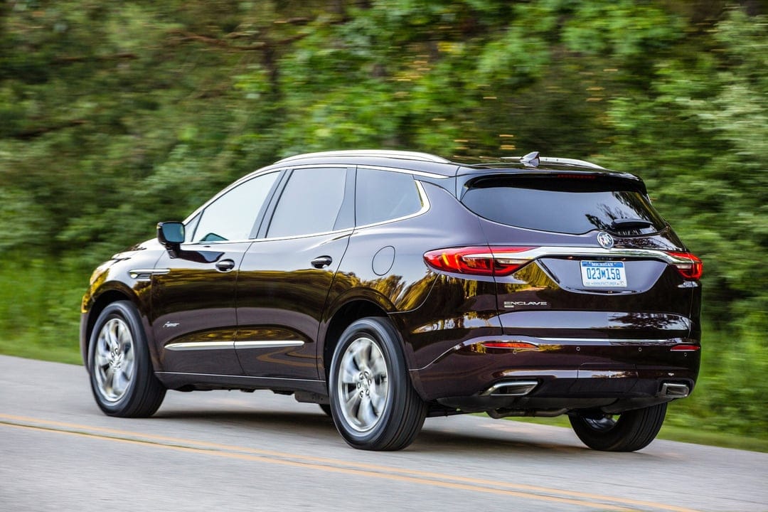 Buick Enclave driving on a forest road with motion blur background and sunlight reflections on the paint.