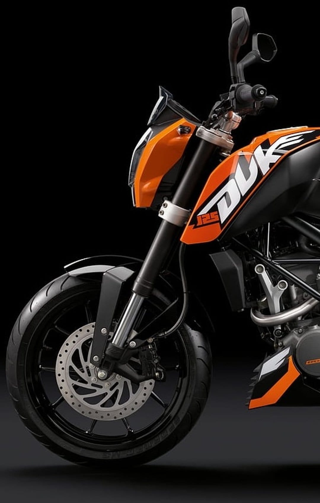 KTM 125 Duke motorcycle front wheel with a perforated disc brake and orange fairing against a black background.