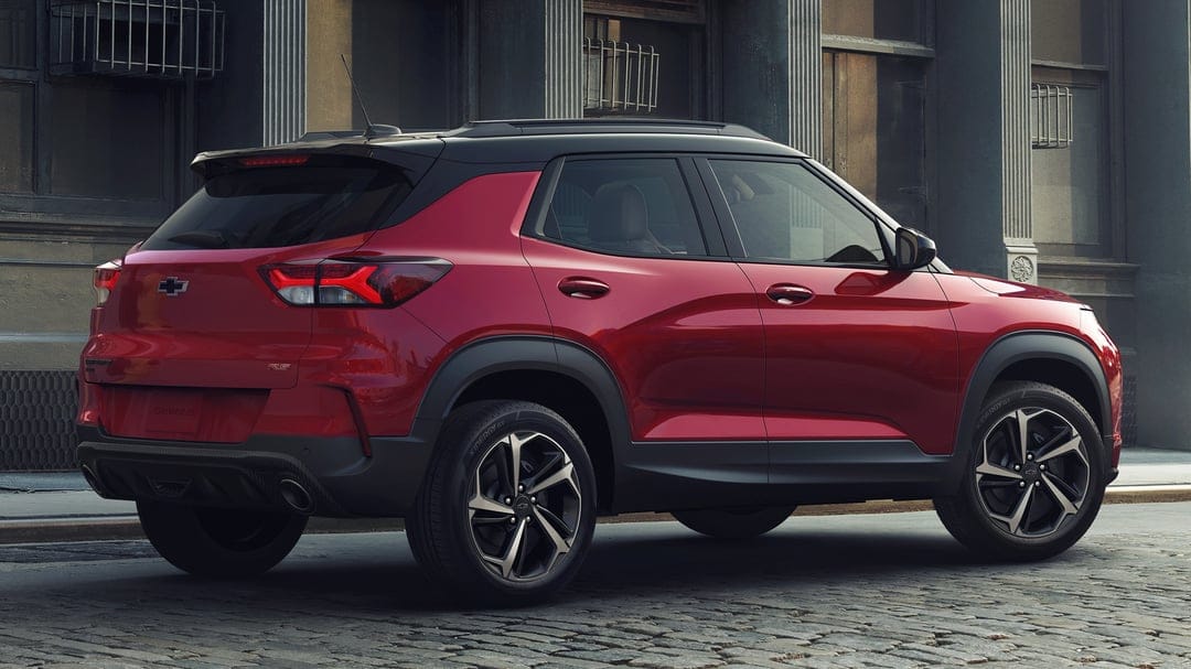 Red Chevrolet Trailblazer RS SUV parked on a cobblestone urban street in front of a stone building.
