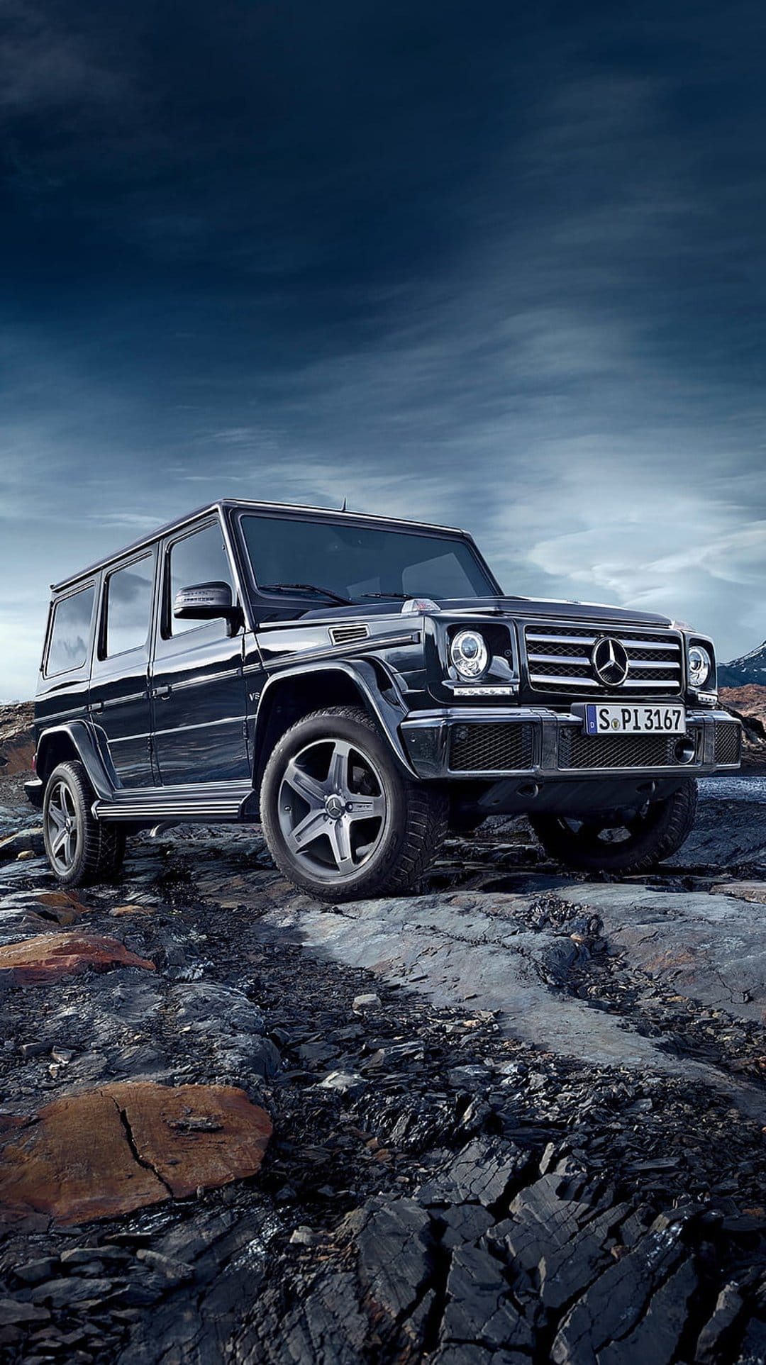 Black Mercedes G-Wagon SUV parked on a jagged rock formation beneath a dramatic, dark and cloudy grey sky.