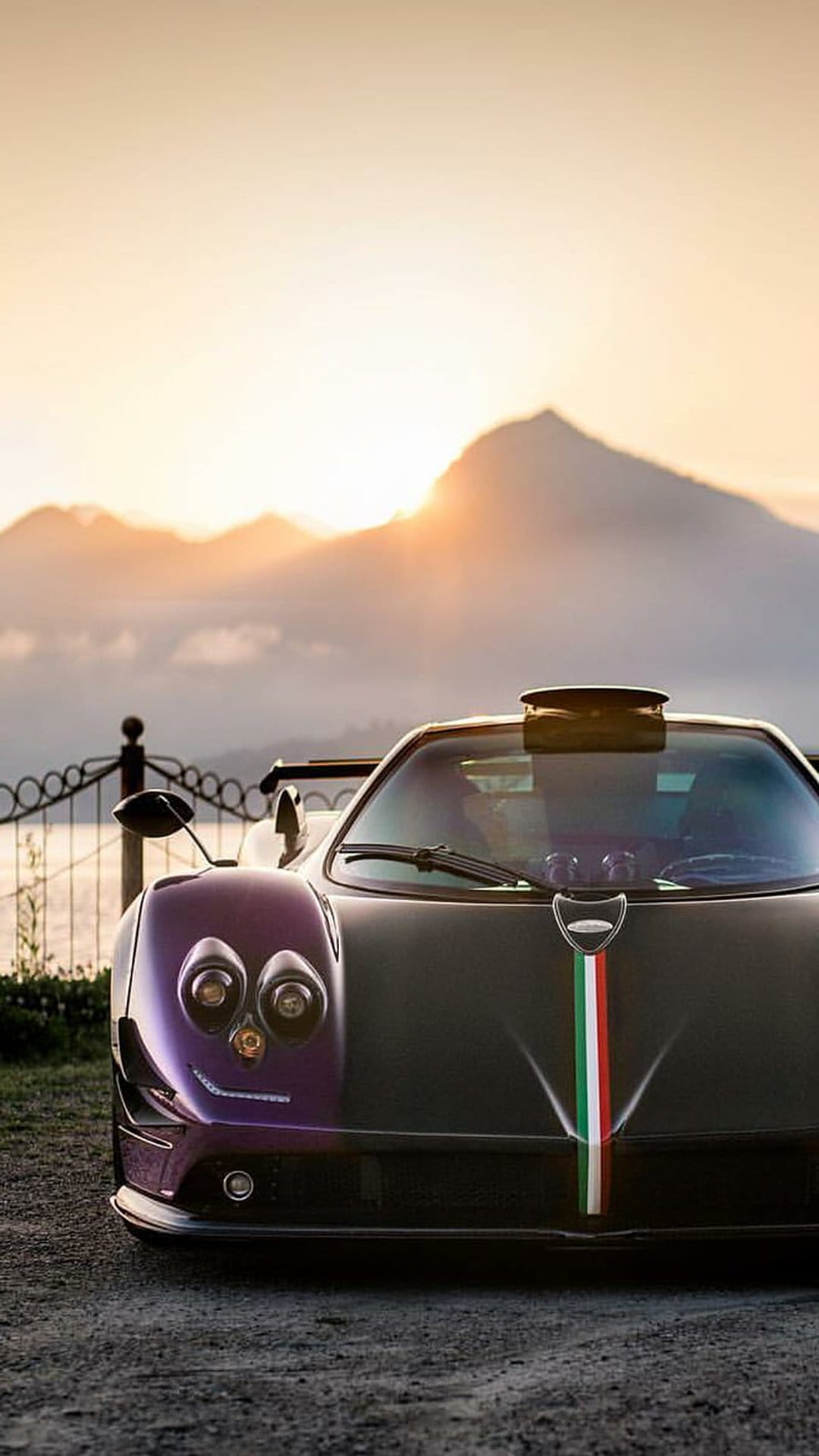 Purple Pagani Zonda on a gravel road with a mountain sunset background and a tricolor stripe on the front.