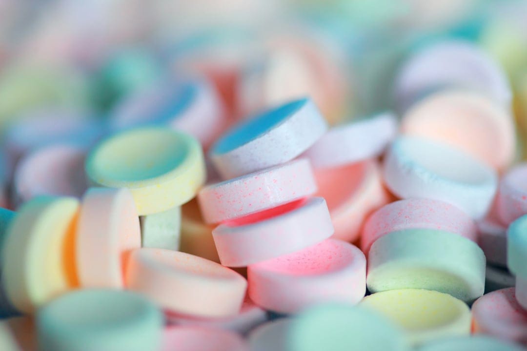 Pastel candy buttons scattered in a macro shot with soft focus, creating a bright and airy textured background.