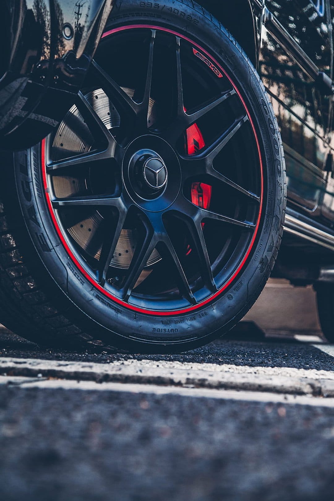 Black Mercedes-Benz G-Wagon wheel with multi-spoke rims, red brake calipers, and a thin red accent stripe.