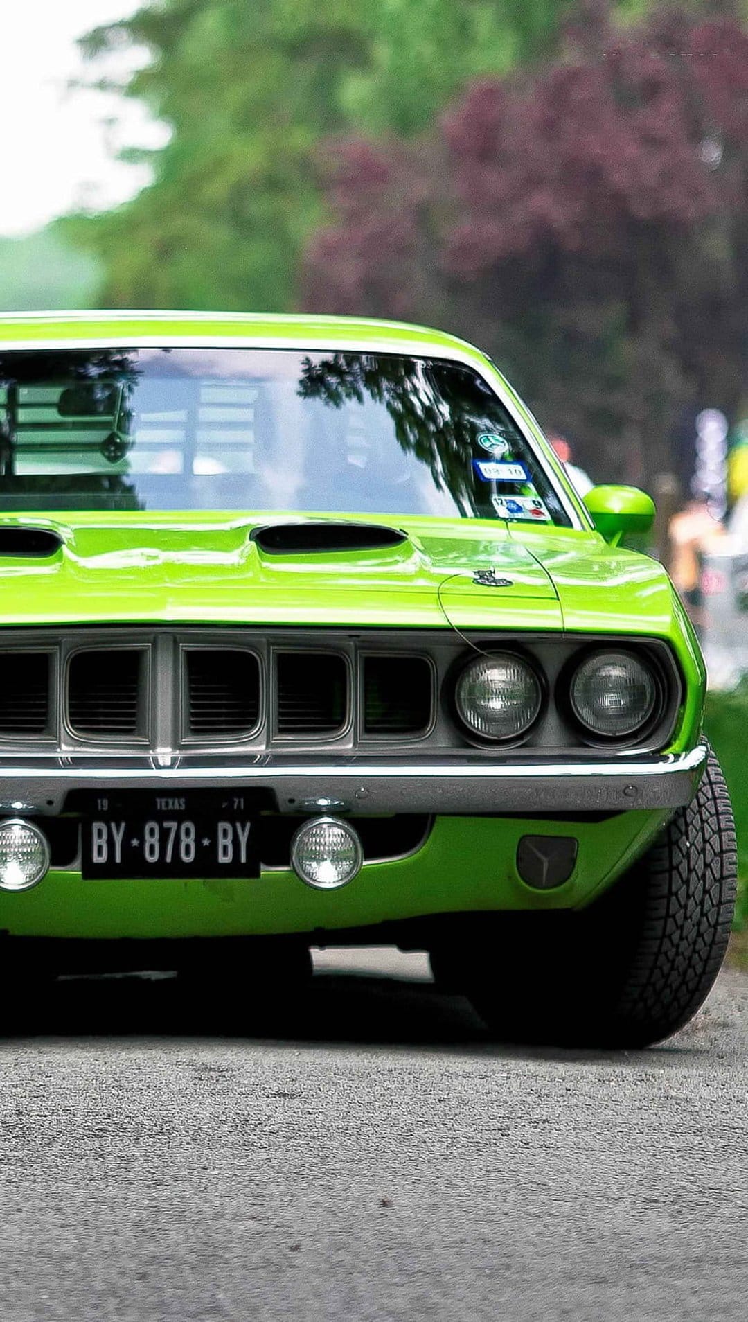 Lime green vintage muscle car with a Texas license plate and dual hood scoops parked in a sunny outdoor setting.