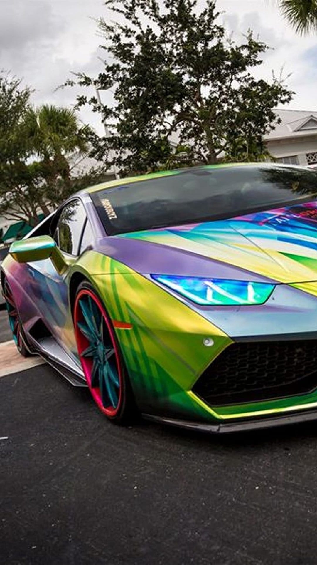 Lamborghini supercar with iridescent rainbow paint and glowing neon wheels against a dark, minimalist background.