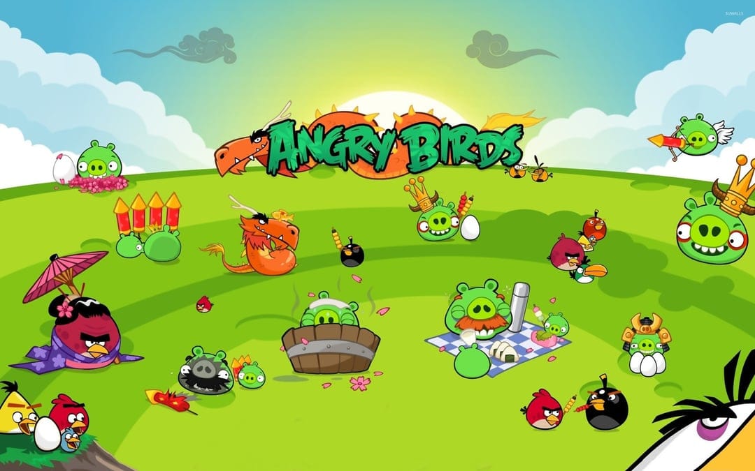 Angry Birds characters and green pigs celebrate Year of the Dragon on a sunny grassy hill with fireworks.