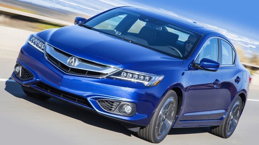 Blue Acura ILX luxury sedan driving fast on a sunlit road with Jewel Eye LED headlights and motion blur.