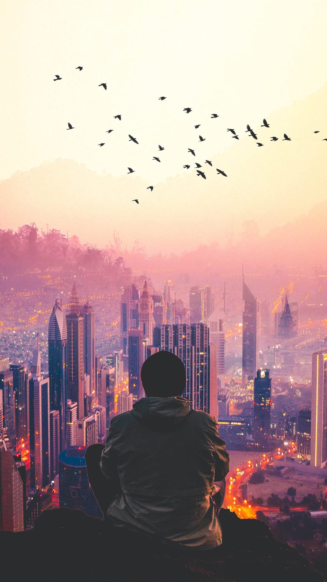 Person sitting on a high ledge overlooking a glowing cityscape at sunset with birds flying through the orange sky