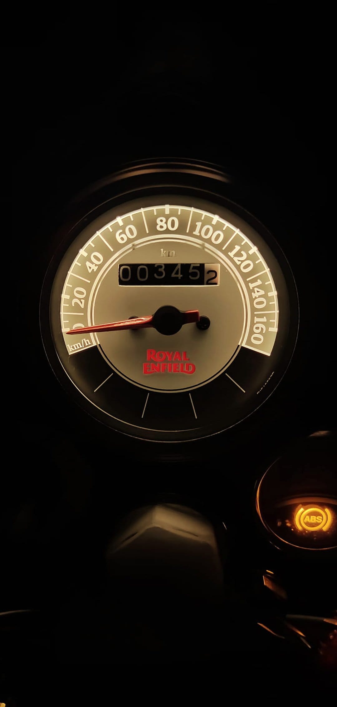 Royal Enfield speedometer with glowing orange ABS light and odometer display showing numerical distance readings.