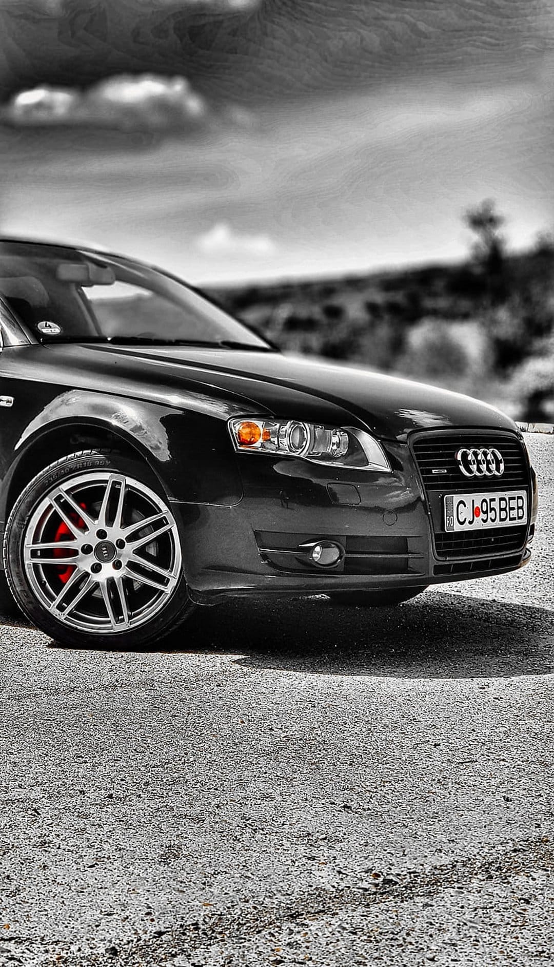 Black Audi A4 front wheel with red brake calipers, silver rings on the grille, and a clear glass headlight.