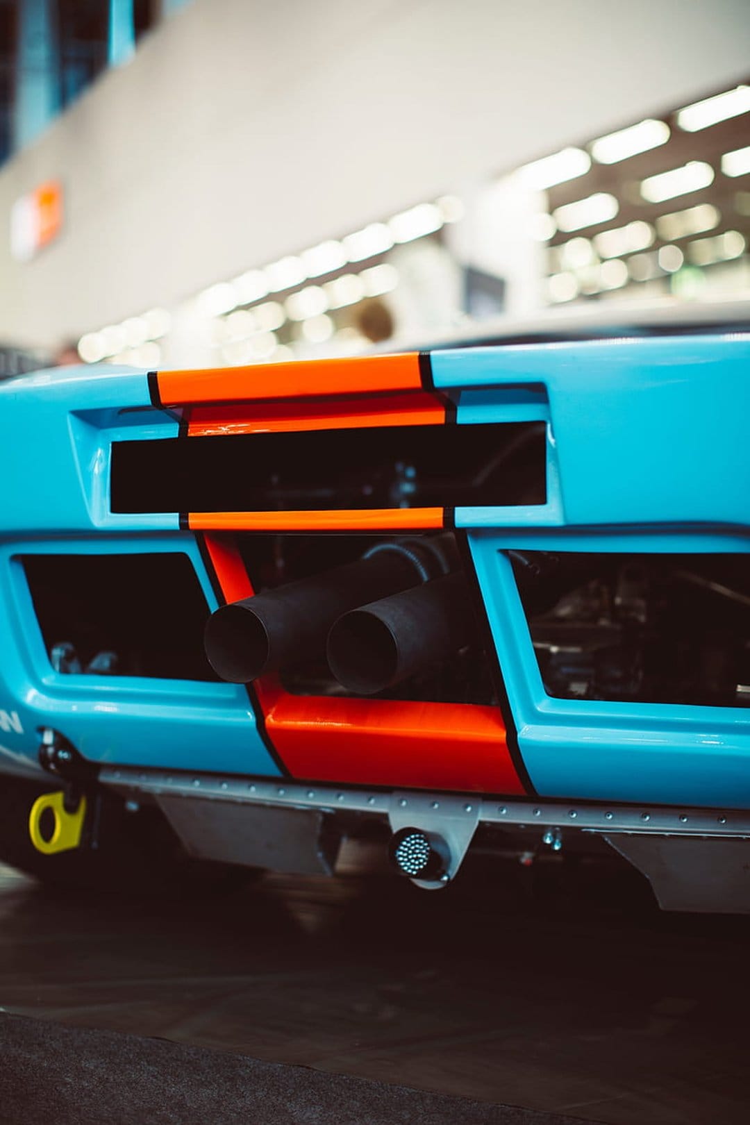 Ford GT40 rear view featuring blue and orange Gulf livery with prominent twin exhaust pipes and mesh vents.