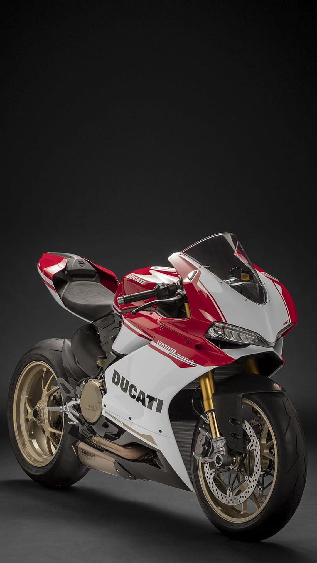 Red and white Ducati motorcycle with gold wheels and fairing logo positioned against a dark studio background.