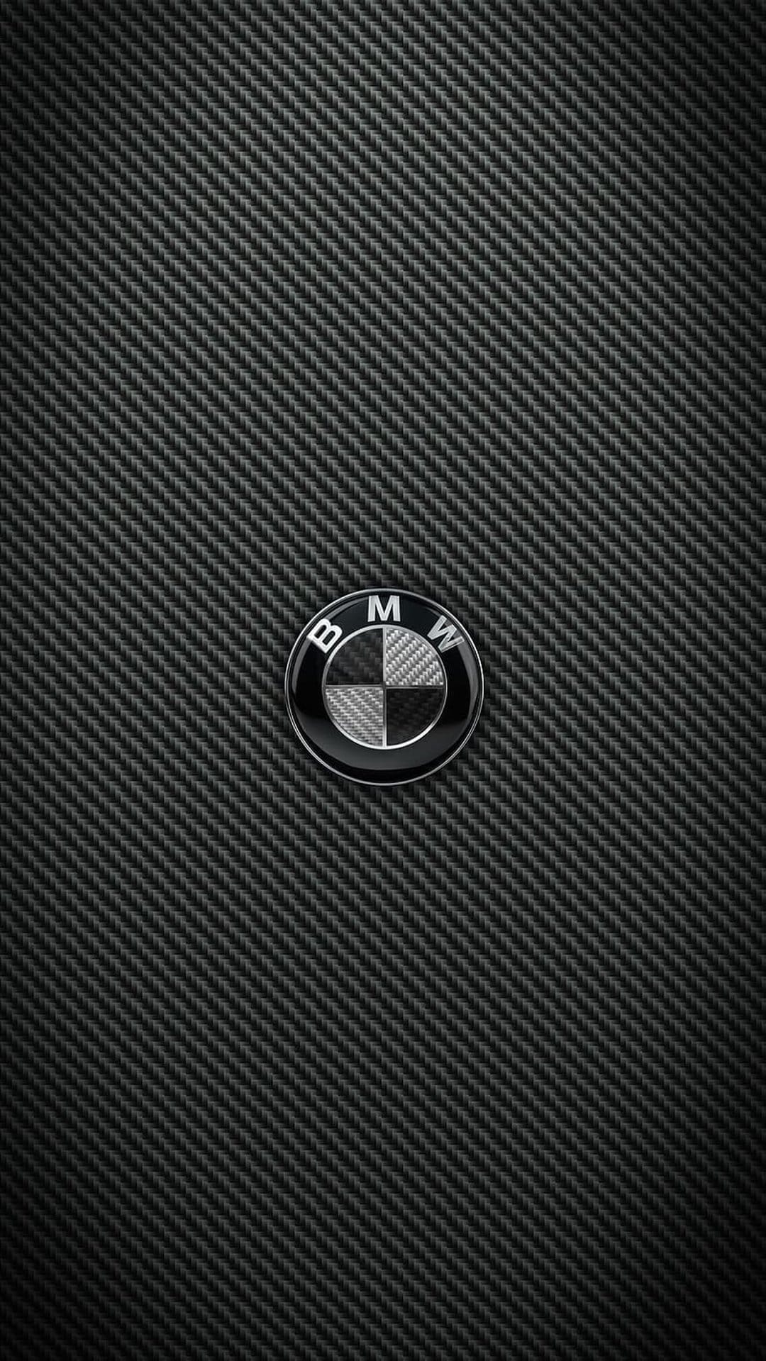 BMW emblem centered on a dark matte carbon fiber background with realistic woven textures and metallic reflections.