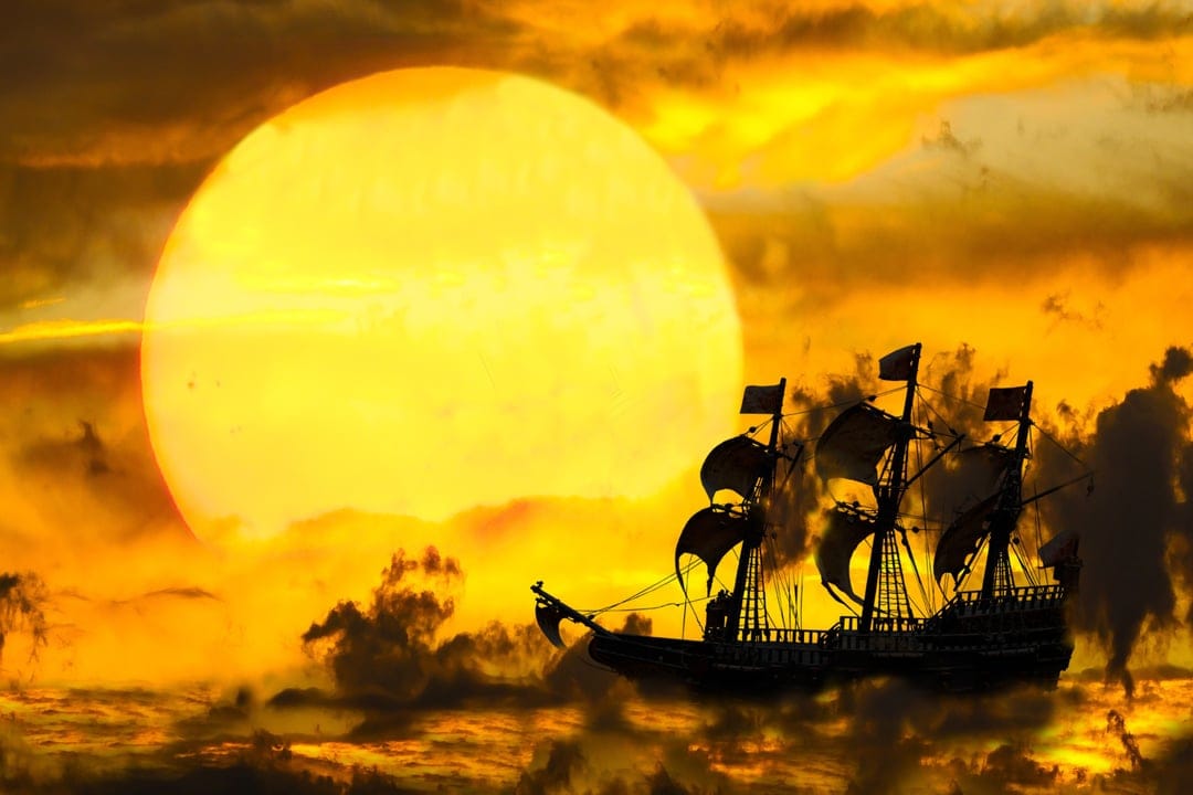 Pirate ship silhouette with billowing sails navigates toward a massive orange sun in a cloudy golden sky.