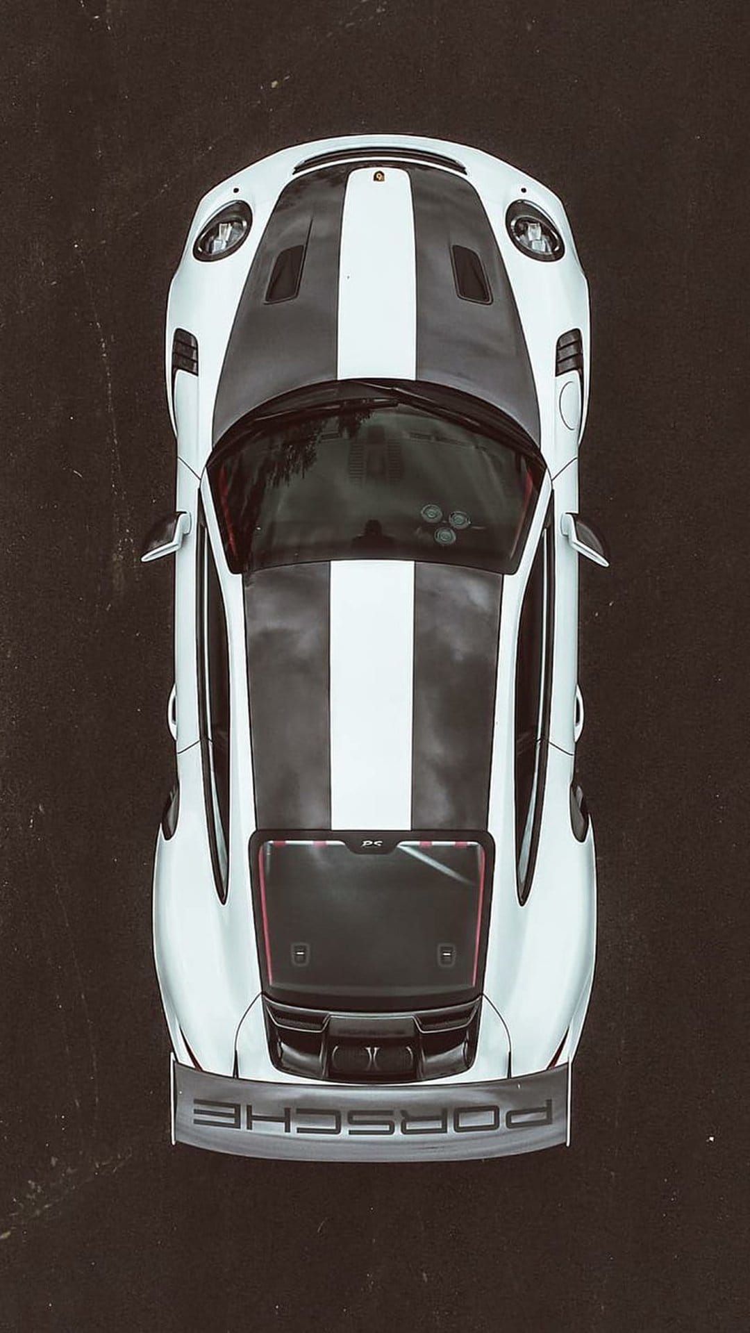 White Porsche 911 GT3 RS with black racing stripes seen from directly above, highlighting the large rear spoiler.