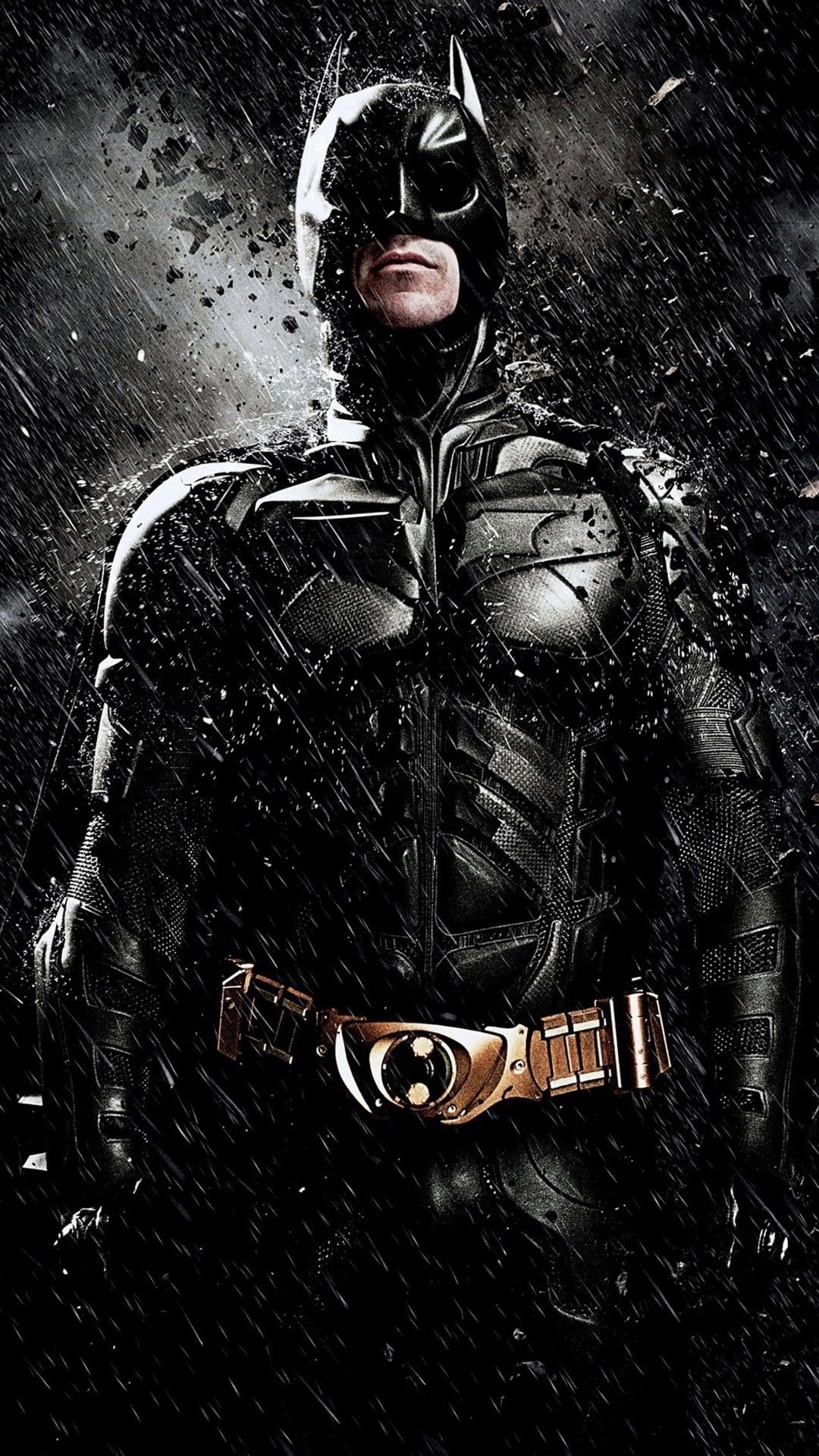Batman in tactical armor stands in a heavy downpour with water dripping off his cowl and a gold utility belt.