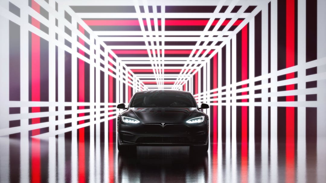 Black Tesla car centered in a futuristic tunnel of glowing red and white geometric light bars with floor reflections.