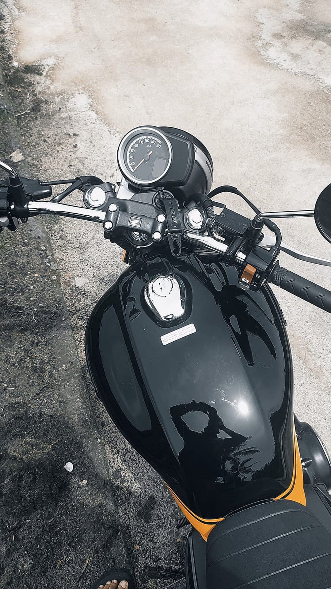 Black and yellow motorcycle fuel tank with chrome handlebars and digital gauges seen from a top-down perspective.