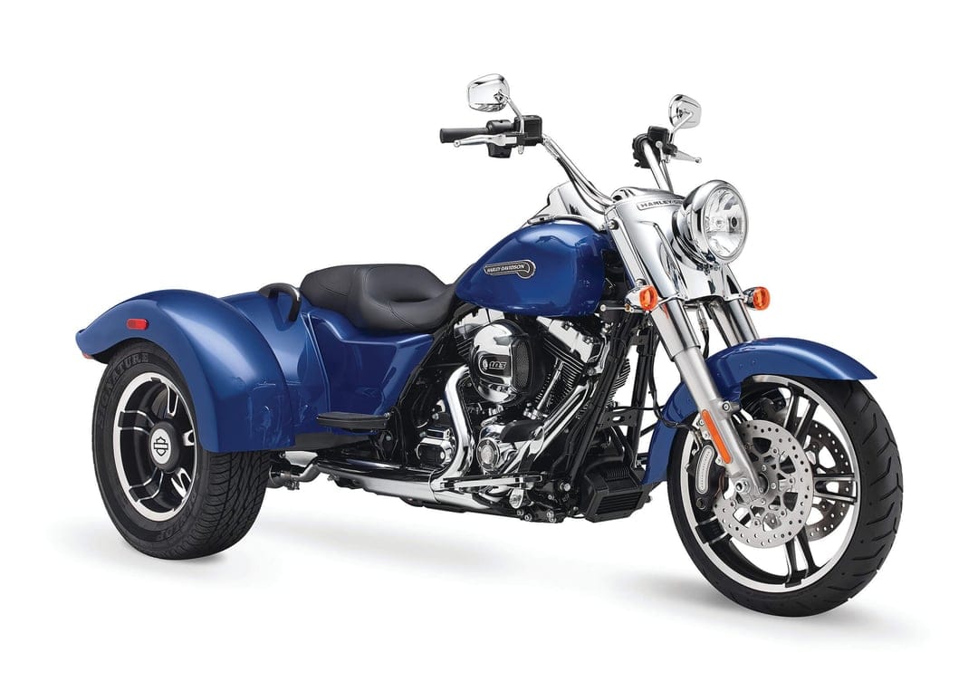 Blue Harley-Davidson three-wheel motorcycle with chrome engine details and black leather seat on white background.