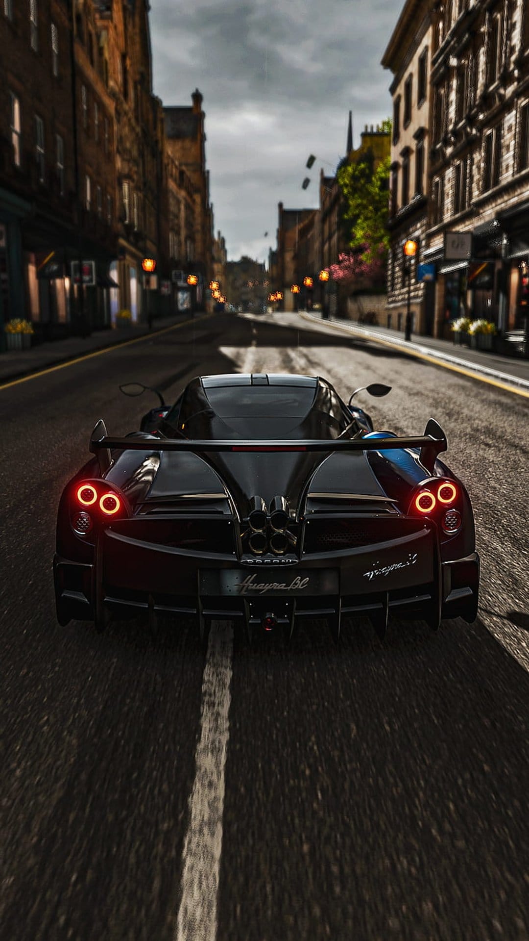 Pagani Huayra BC supercar with red taillights driving on wet cobblestone streets under warm city streetlamps.