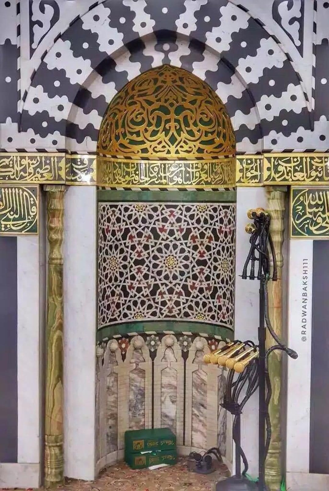 Golden Arabic calligraphy and intricate geometric tile patterns decorate a circular mosque dome ceiling.