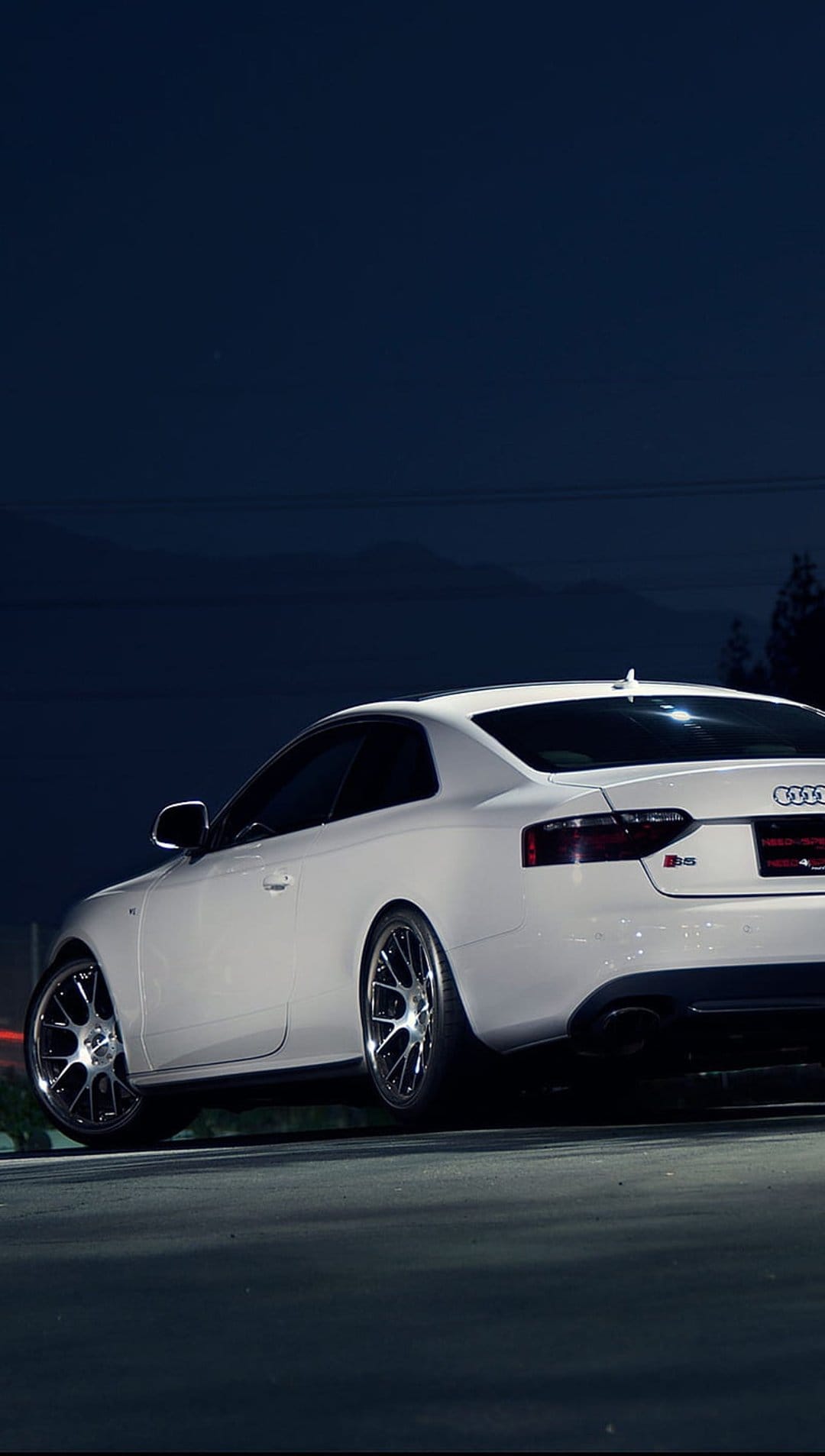 Audi RS5 coupe in white parked on dark asphalt at night featuring sharp body lines and polished alloy wheels.