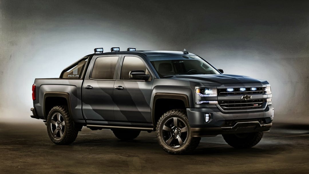 Chevrolet Silverado Special Ops truck with matte camouflage wrap, LED lights, and off-road tires in a dark studio.