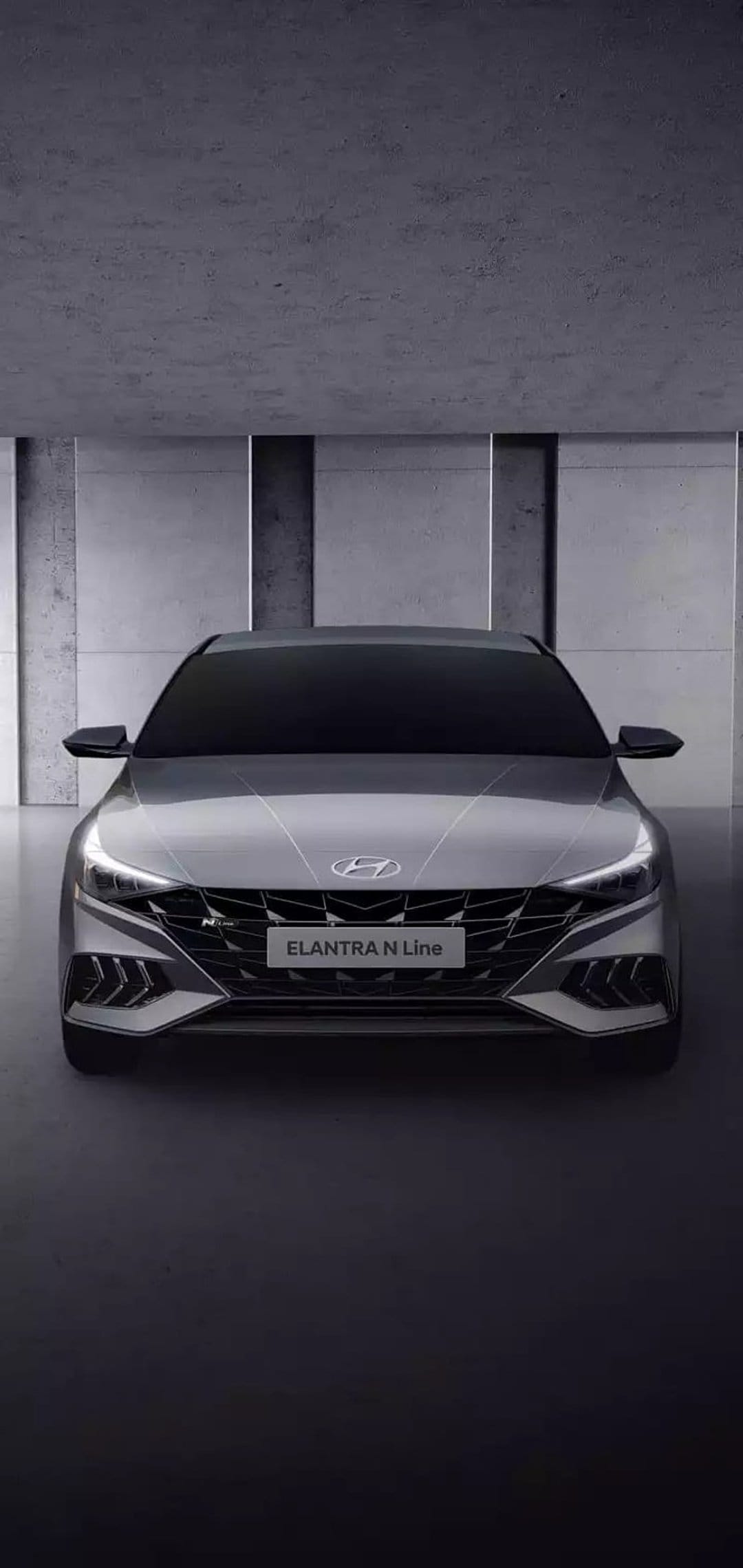 Hyundai Elantra N Line front fascia with a black mesh grille and sharp LED headlights in a modern garage setting.