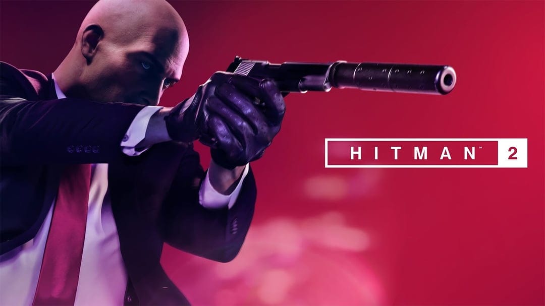 Agent 47 aims a silenced pistol against a vibrant red background in this Hitman 2 gaming scene.
