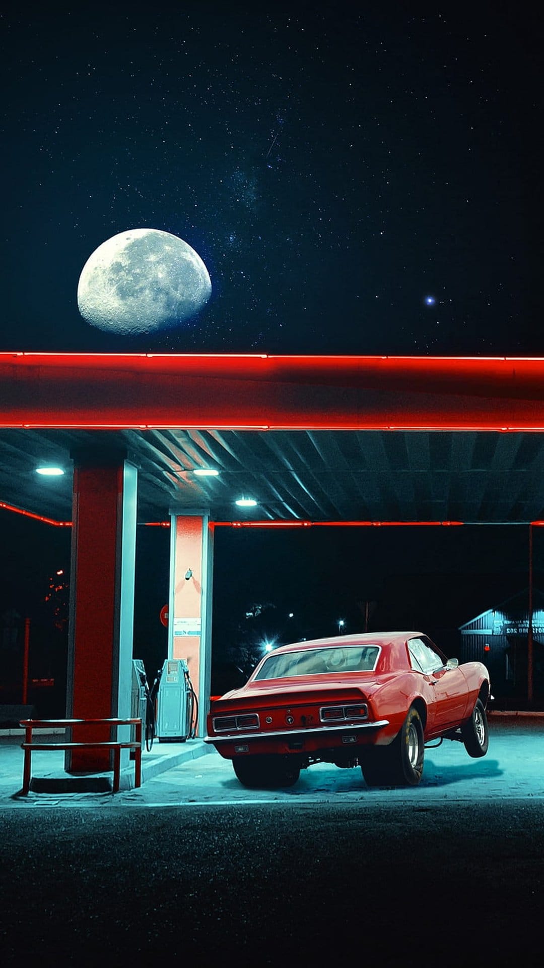 Red Camaro muscle car doing a wheelie at a gas station under a full moon with neon lights and starry sky.