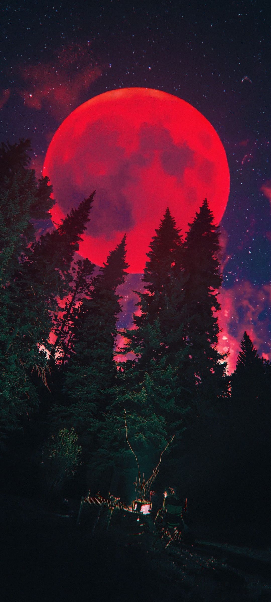 Giant red moon rising above silhouetted pine trees with a small glowing campfire burning in the dark foreground.
