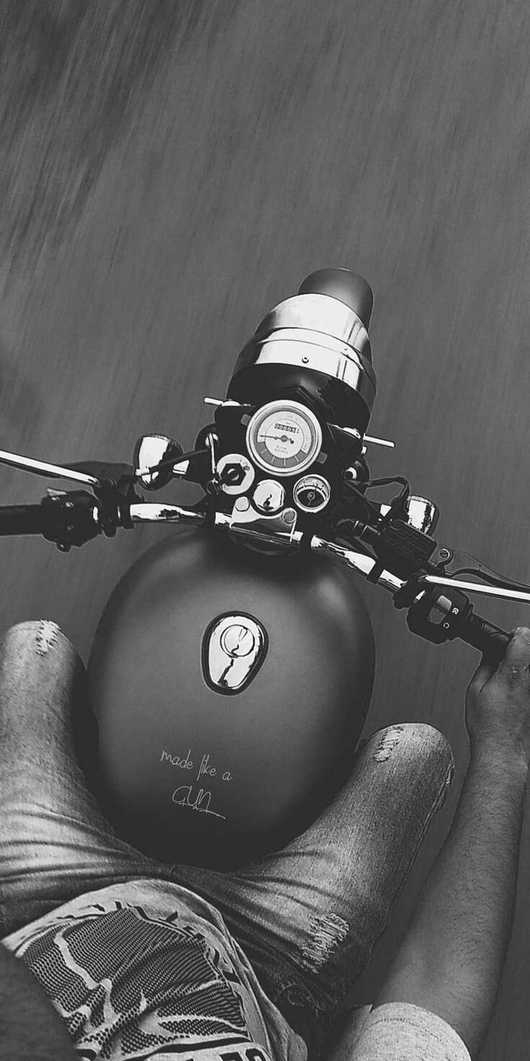 Royal Enfield handlebars and fuel tank seen from a rider's perspective with motion blur and denim jeans.