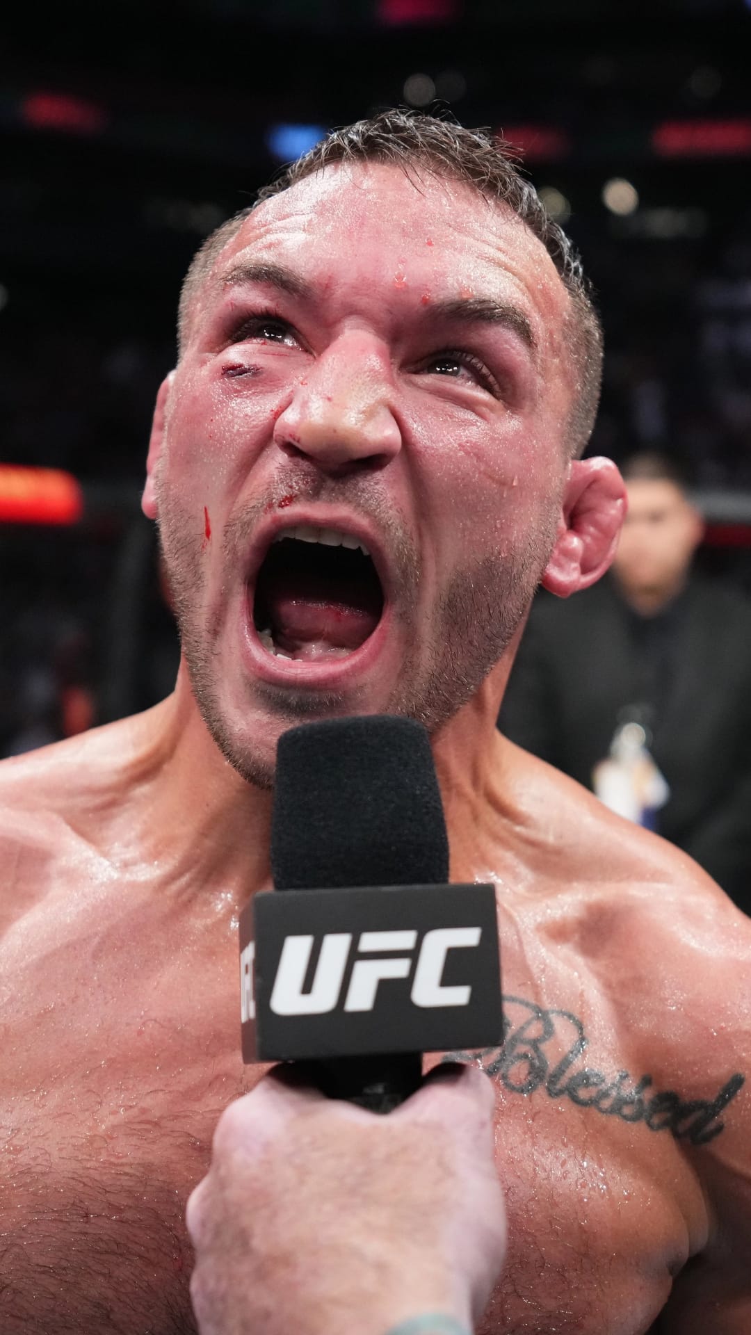 Michael Chandler shouts during a post-fight interview, featuring a Blessed tattoo and glistening sweat texture.