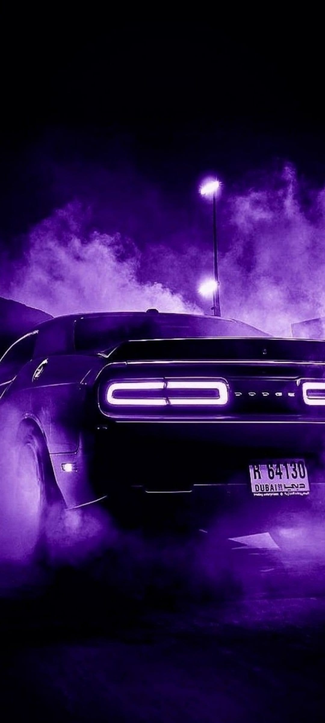 Purple Dodge Challenger with glowing taillights and thick violet smoke on a dark Dubai street at night.