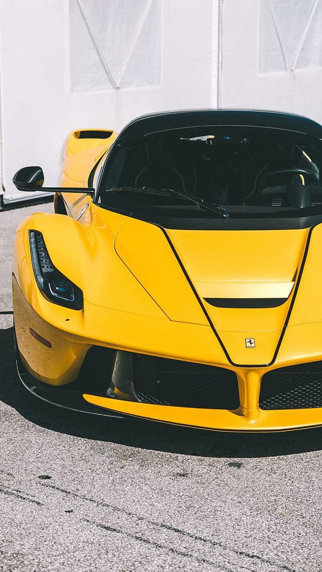 Yellow Ferrari LaFerrari front view featuring sleek LED headlights, a black roof, and the prancing horse emblem.