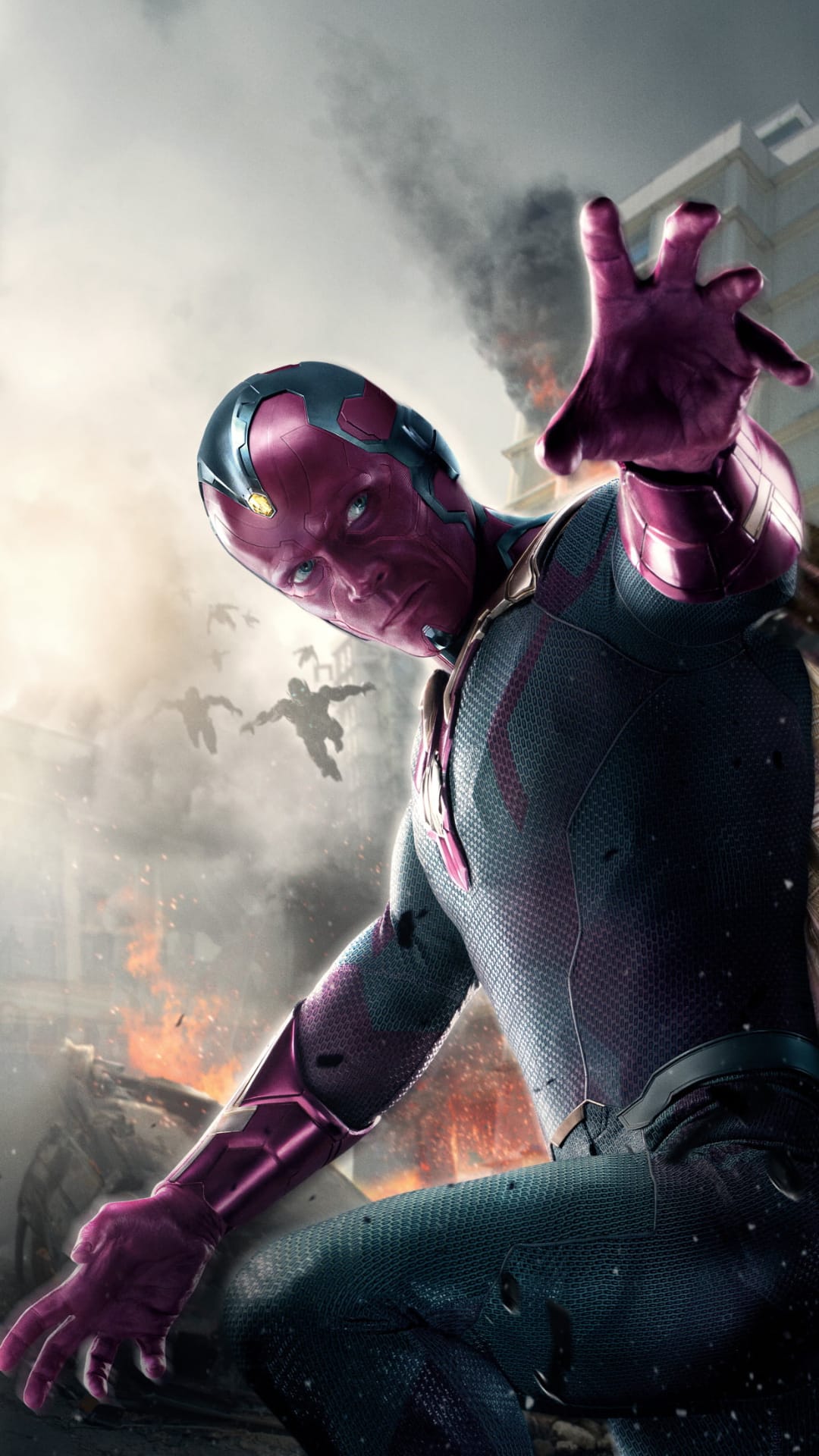 Vision reaches forward with glowing eyes amidst smoke, explosions, and flying figures in a ruined city battle.