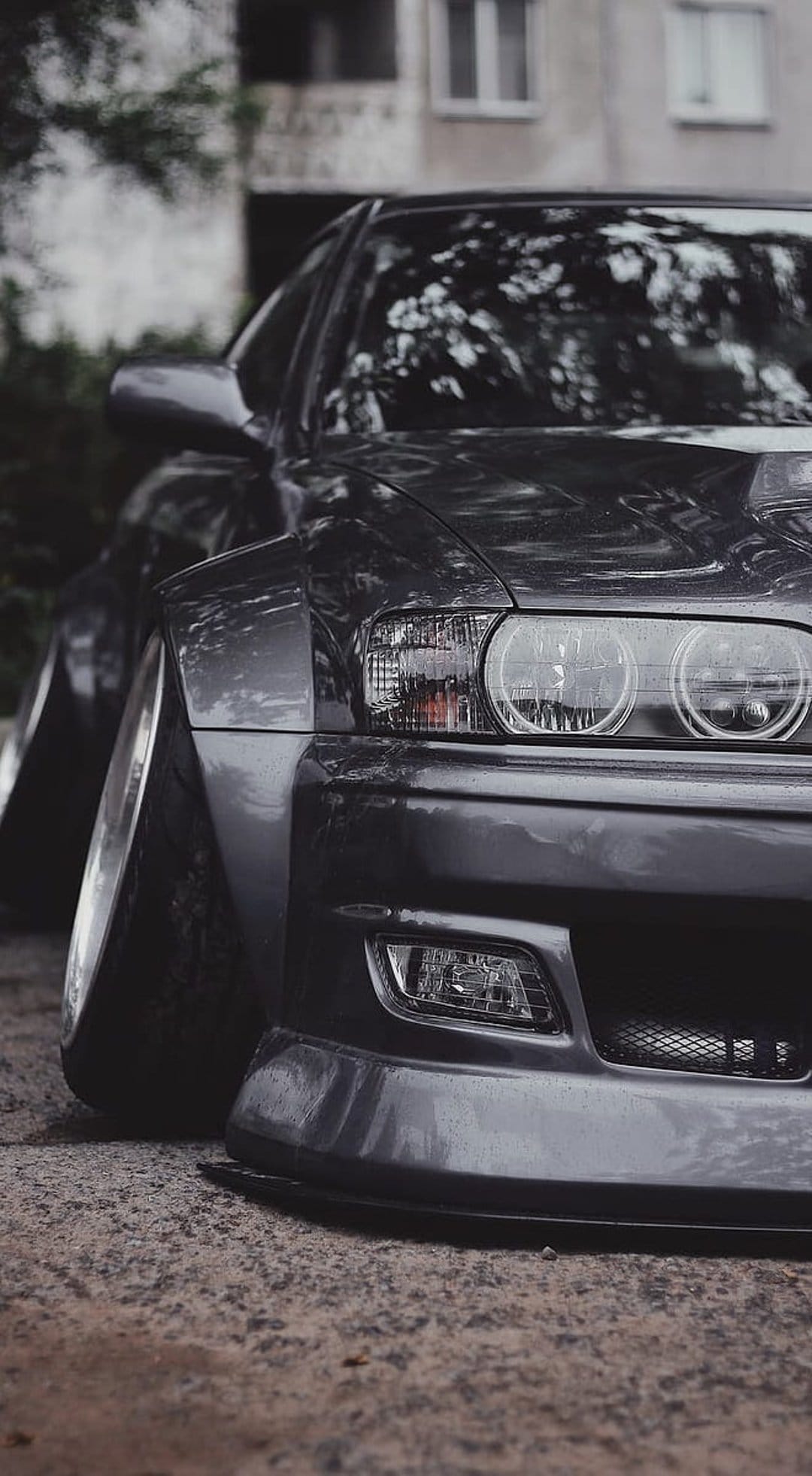 Nissan Silvia S15 widebody car with a slammed stance parked on dark asphalt under soft urban lighting.