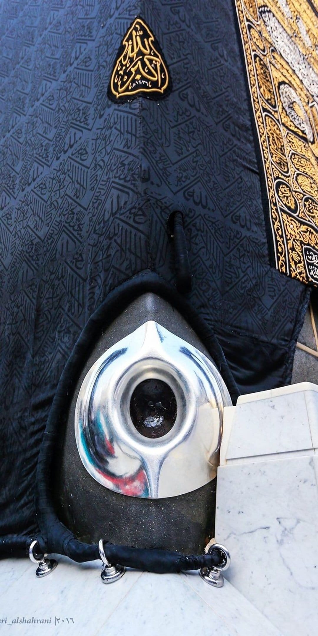 Hajar al-Aswad in a silver frame against black Kiswah fabric with golden Arabic calligraphy in Mecca.