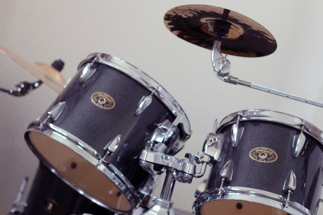 Dark sparkling tom-tom drums with chrome hardware and a shiny cymbal positioned in a detailed close-up shot.