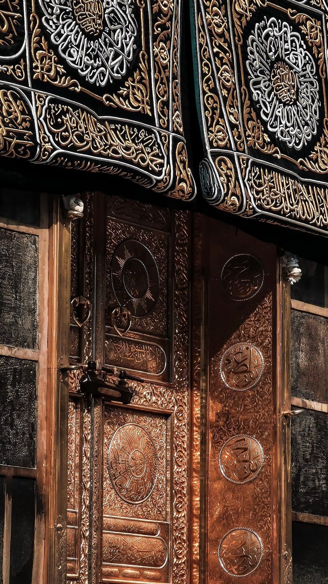 Ornate golden Kaaba door featuring intricate Arabic calligraphy beside the black silk Kiswah with gold embroidery.