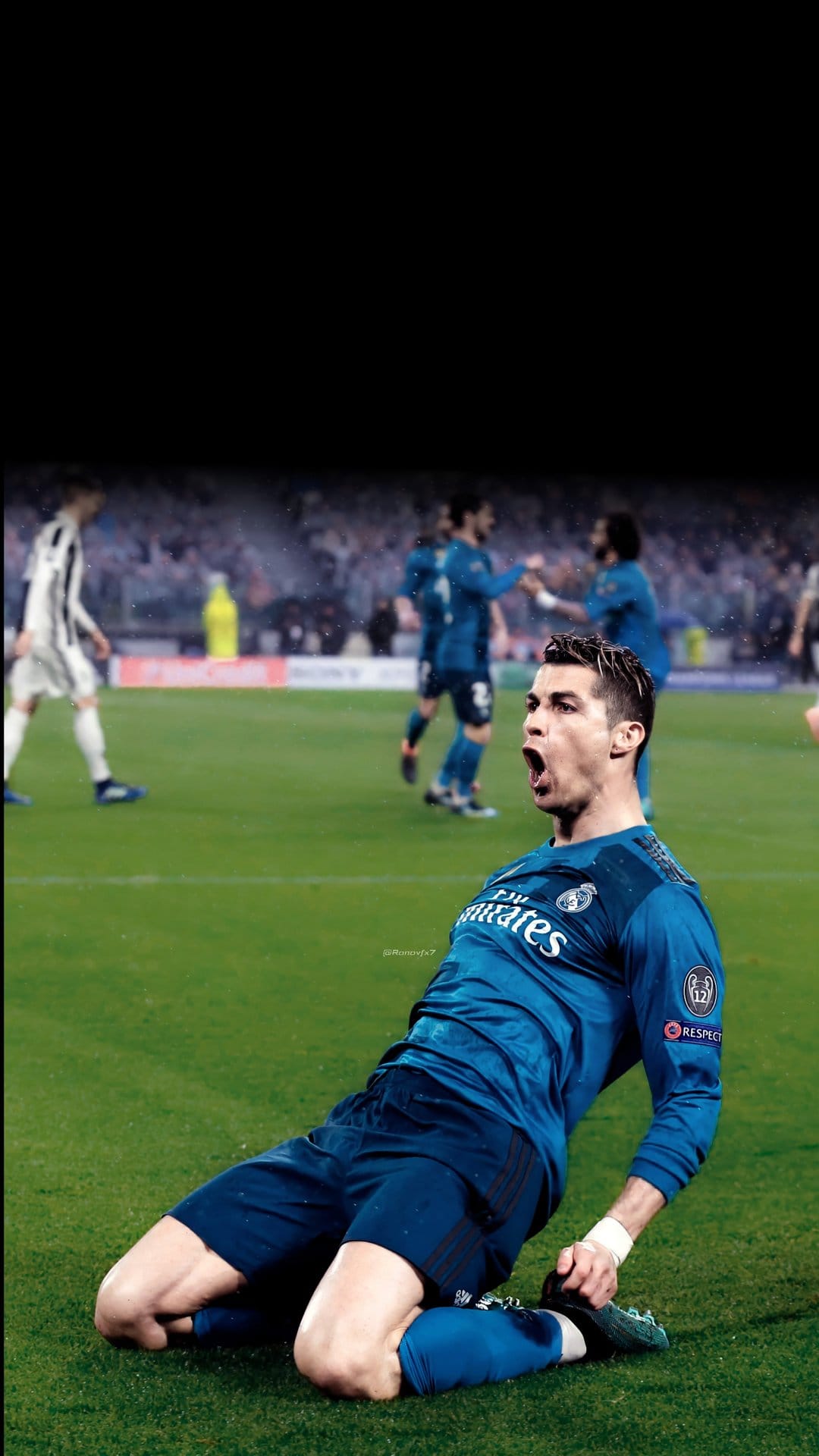 Cristiano Ronaldo kneels on green stadium grass in a blue jersey while shouting during a goal celebration.