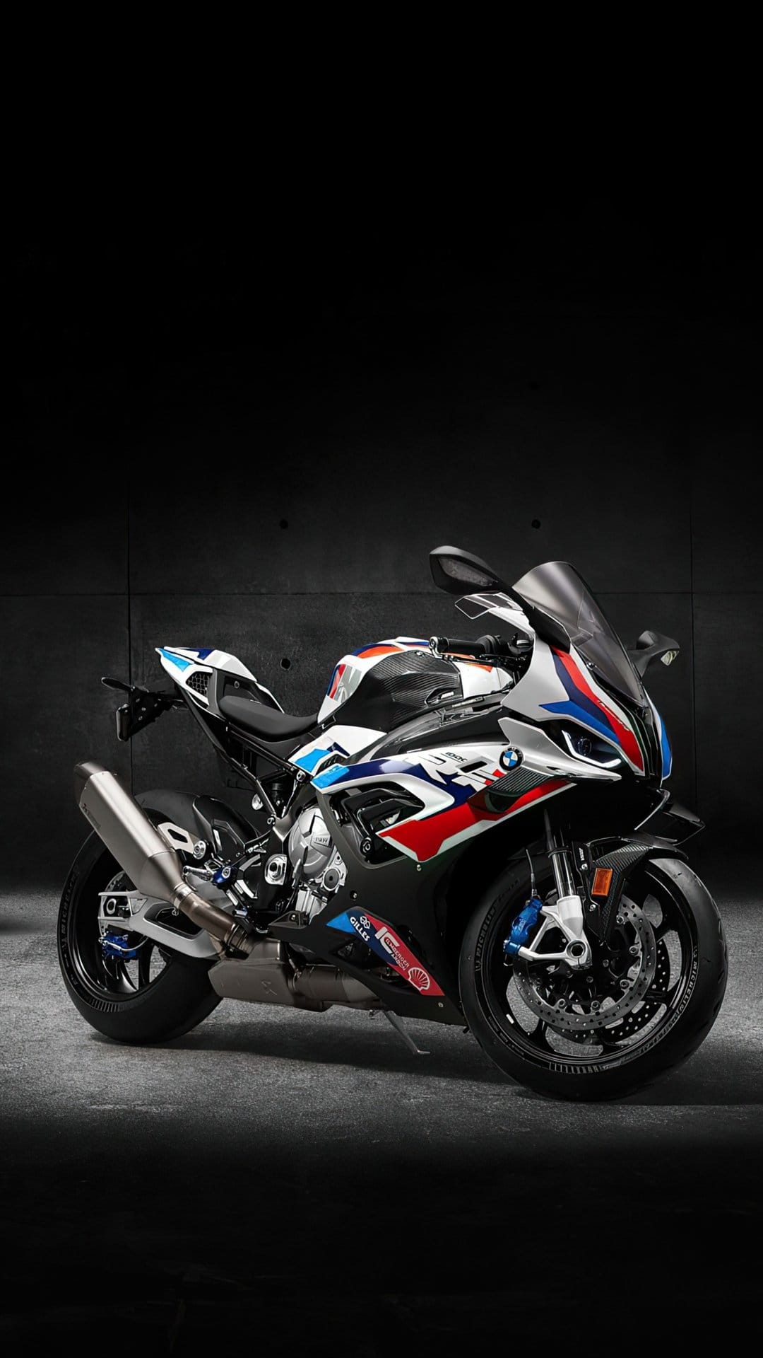 BMW S 1000 RR motorcycle with racing decals parked against a dark background in a vertical studio composition.