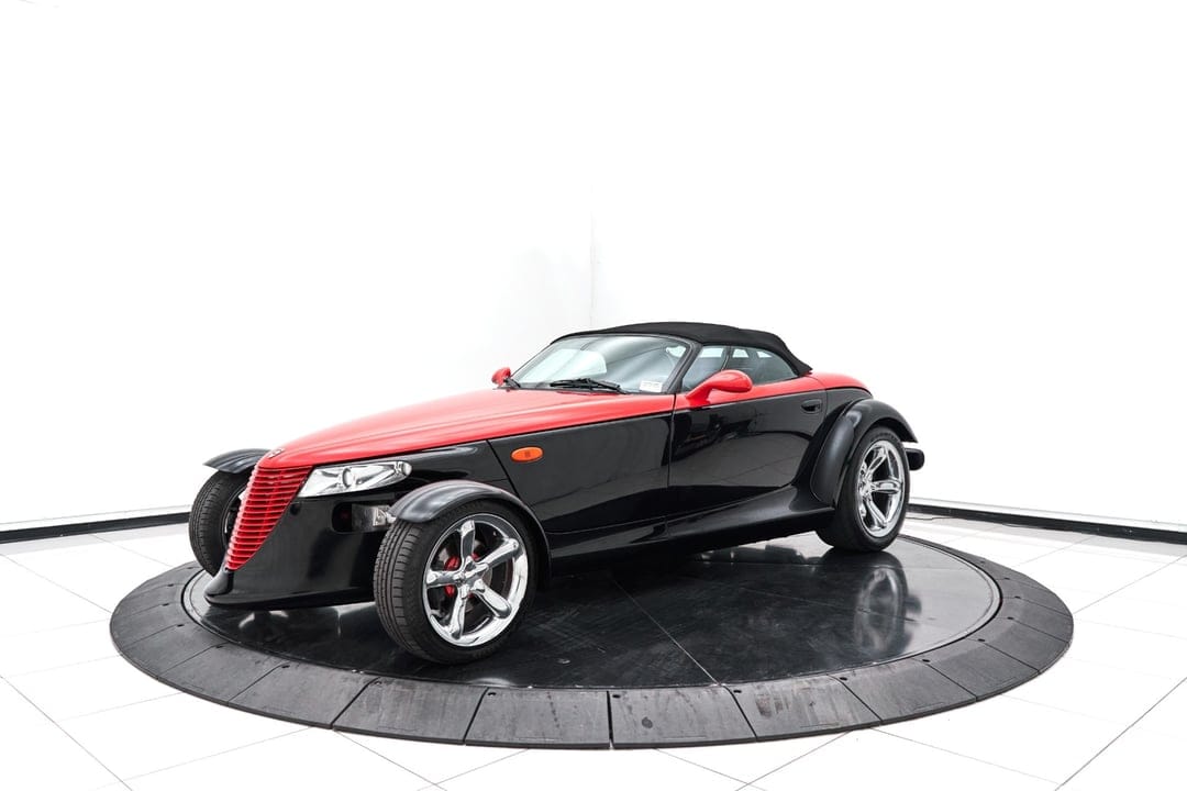 Black and red Plymouth Prowler on a dark circular platform with chrome wheels against a white studio backdrop.