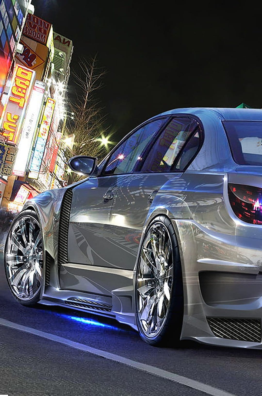 Silver modified sedan with blue underglow parked on a city street at night with blurred neon signs in the background.