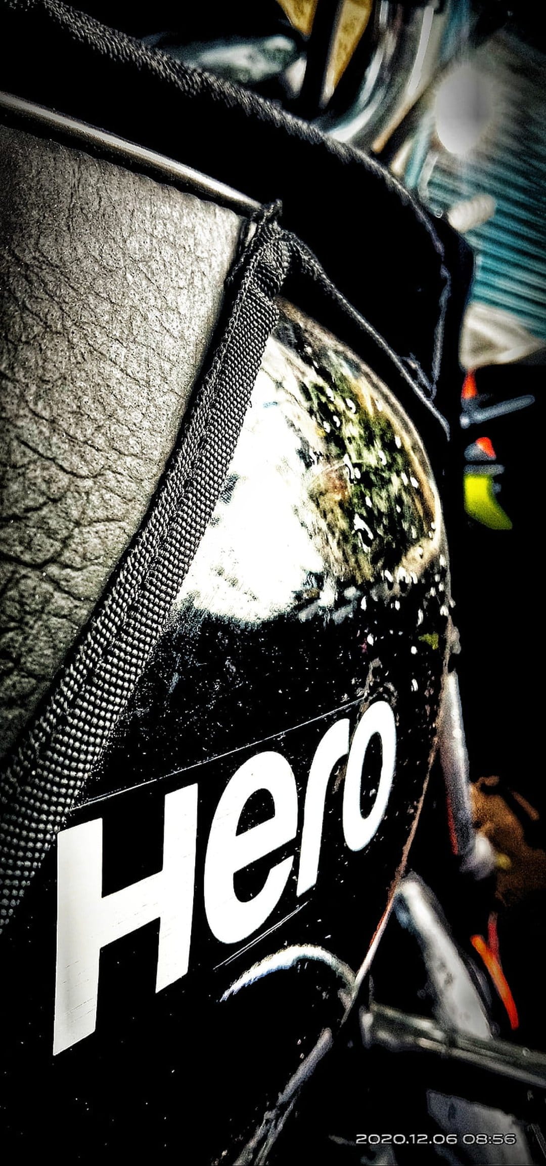 Hero motorcycle logo printed on a wet, black textured leather seat with reflective water droplets in close-up.