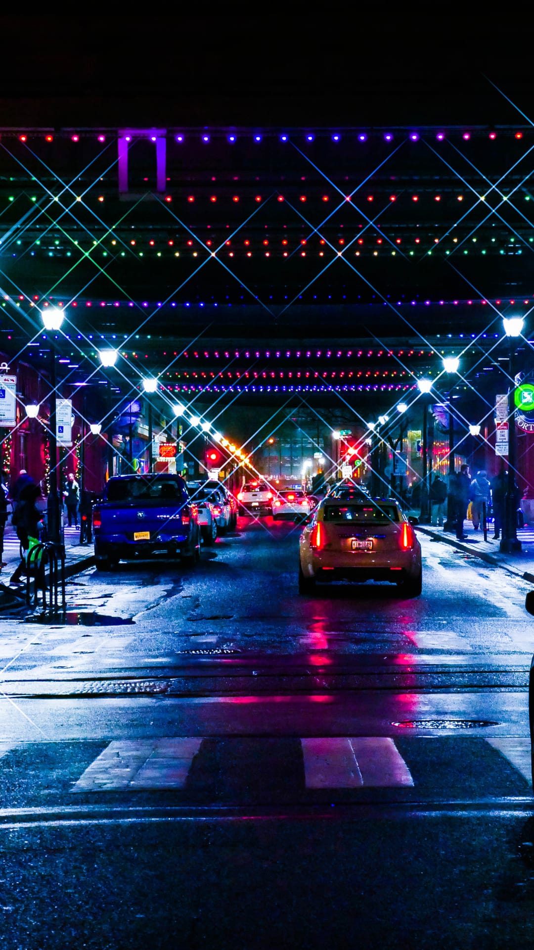 Festive lights hang over a wet Islamabad street with car taillights reflecting on the rain-slicked asphalt.