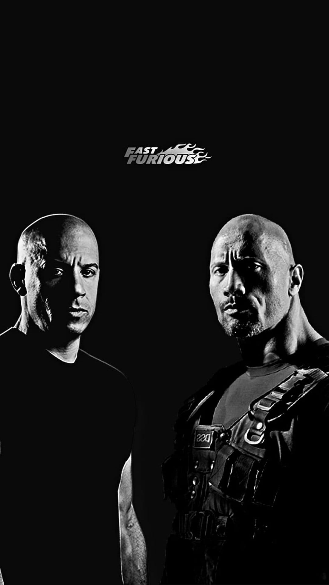 Vin Diesel and Dwayne Johnson pose in a high-contrast black and white portrait with a dark, dramatic background.